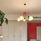 Distant view of this Clérachic pendant glowing high in a room with white cupboards, a red wall and a potted plant.