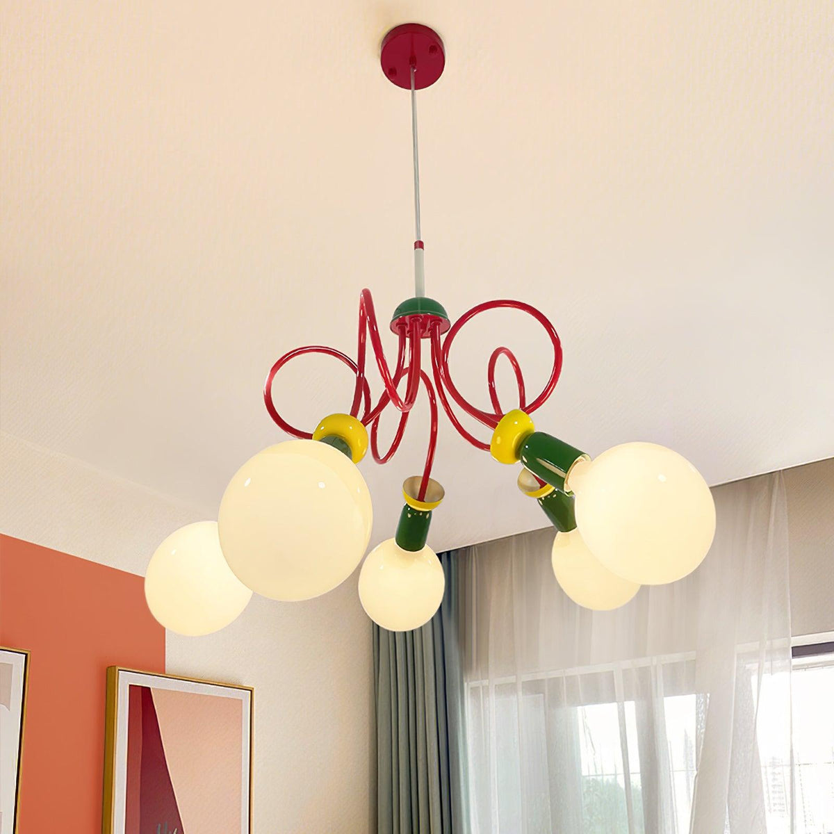 Lit globes under a red ceiling plate on this Clérachic pendant, beside an orange wall, framed art and sheer curtains.