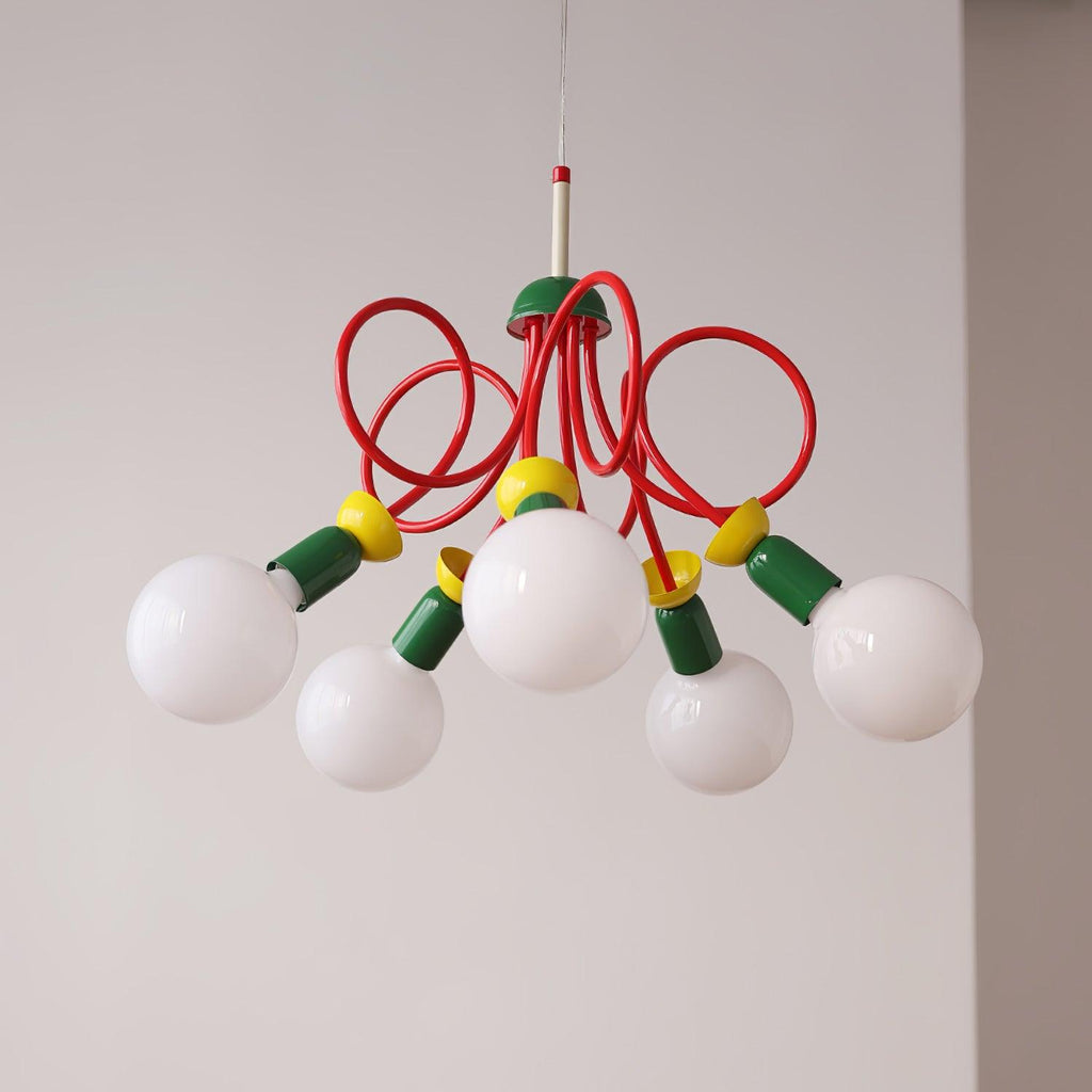 Five white globes hang beneath red looping tubes on this Clérachic pendant, shown against a soft light grey wall.