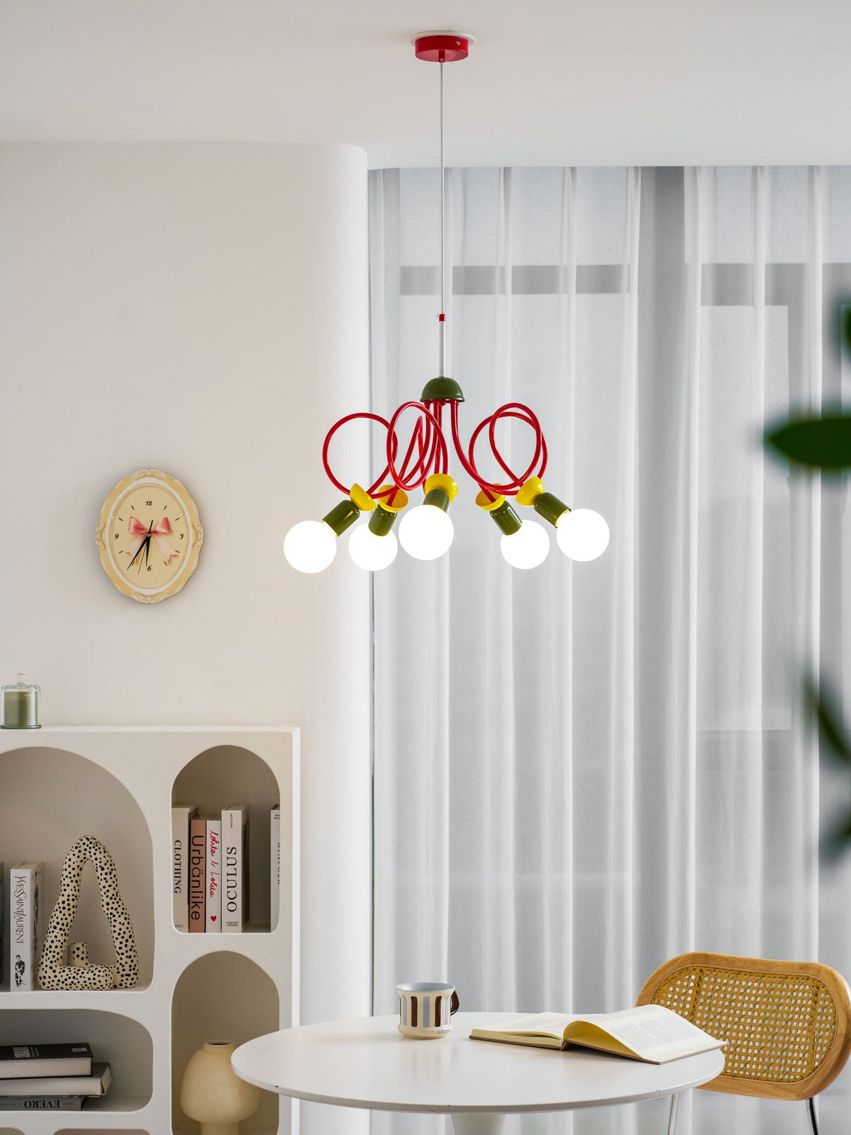This Clérachic pendant hangs by sheer curtains, with a round wall clock, arched shelving and a cane chair below it.
