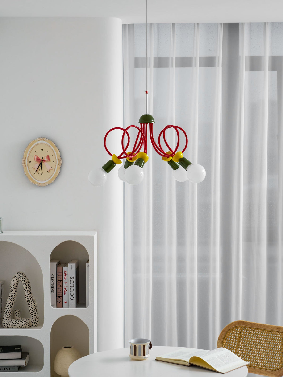 Narrow view of this Clérachic pendant in a white interior, a tall curtain behind and a table with a book below.
