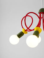 Detail of two globe bulbs, yellow collars and green sockets on this Clérachic pendant, with red tubes curling above.