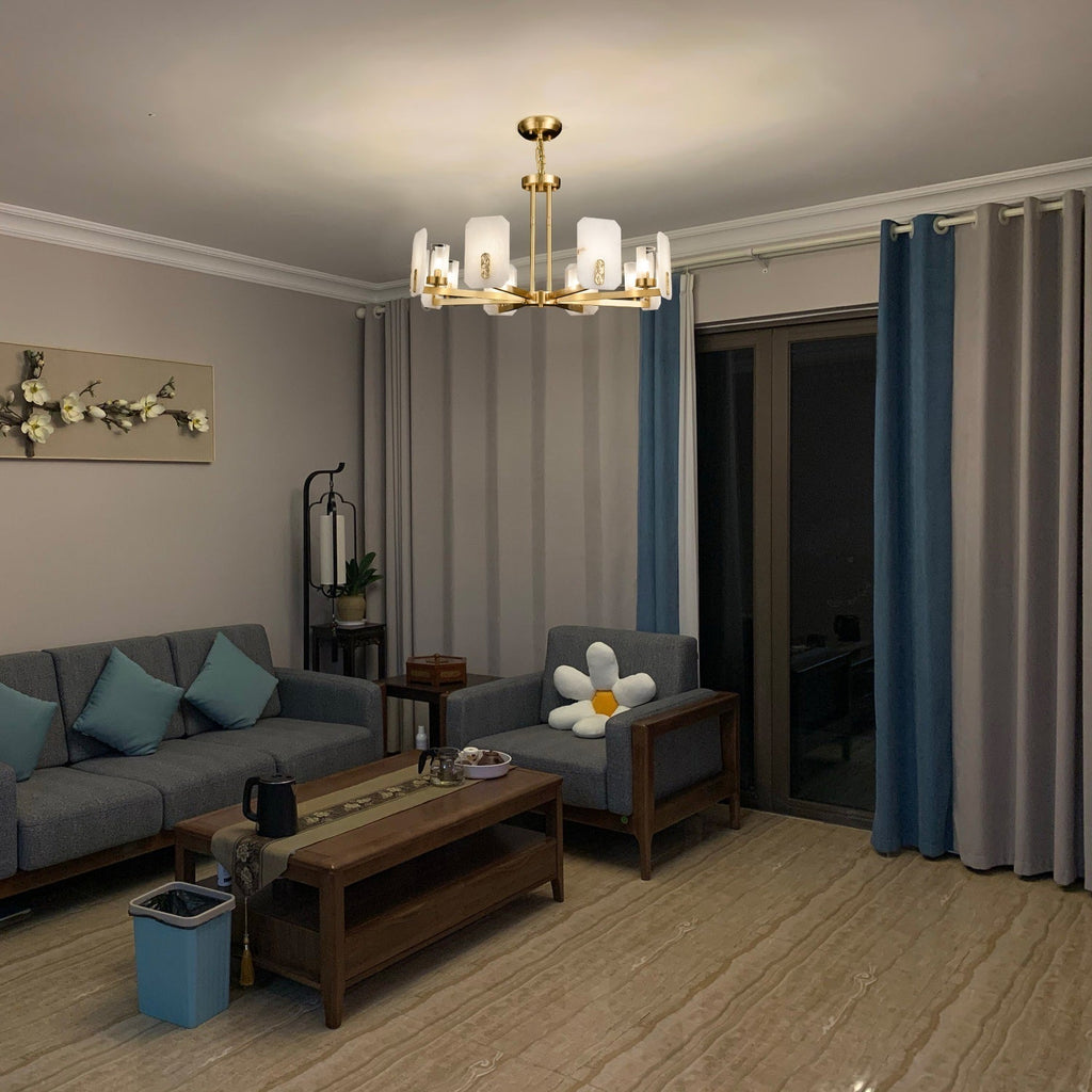 Clérachic Meridian Alabaster Chandelier lighting a grey-sofa living room at dusk, its warm glow washing across the ceiling.