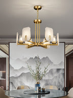 Clérachic Meridian Alabaster Chandelier hanging close over a round dining table, brass arms level with an ink-wash mountain canvas.