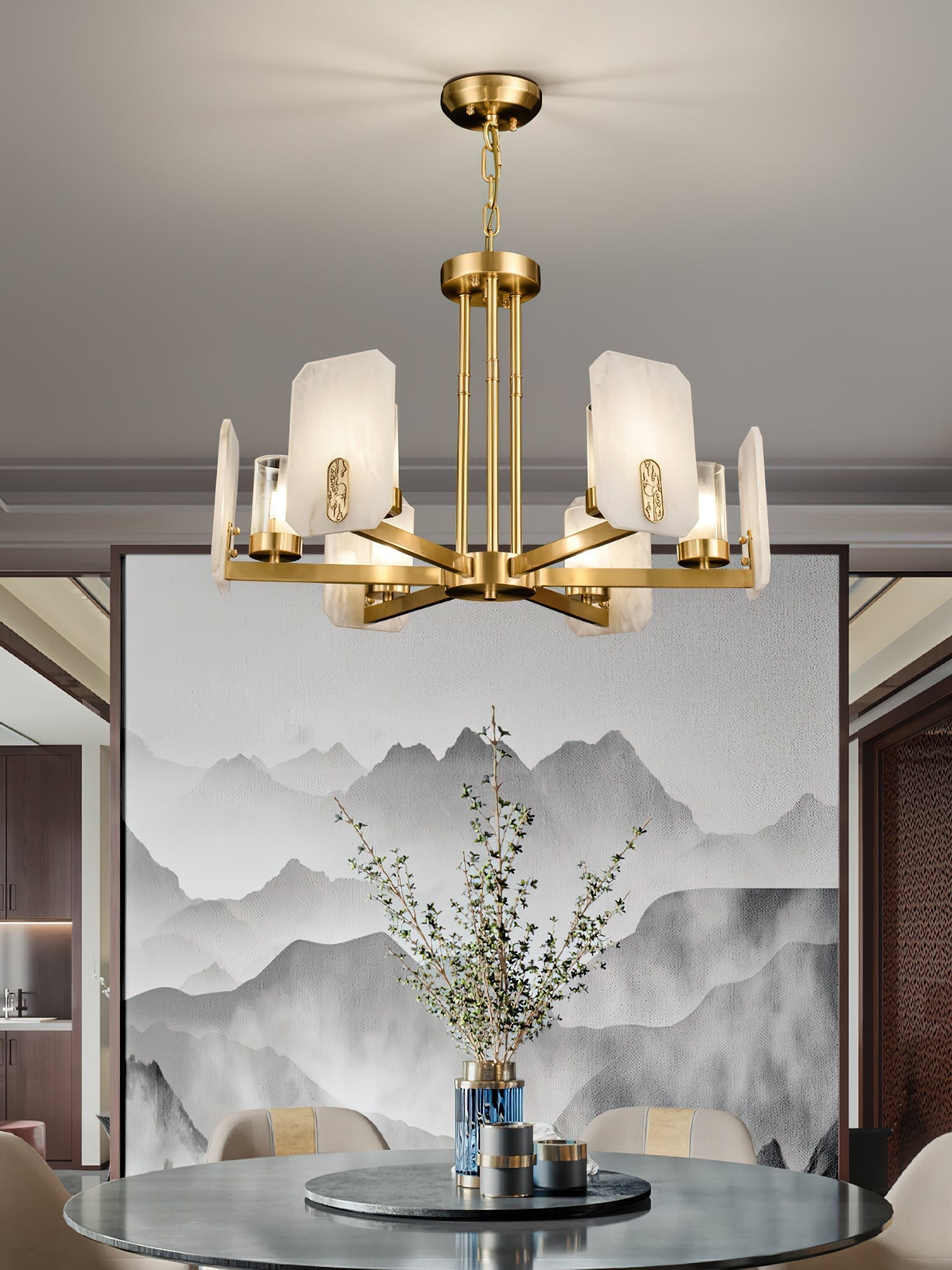 Clérachic Meridian Alabaster Chandelier hanging close over a round dining table, brass arms level with an ink-wash mountain canvas.