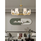 Clérachic Meridian Alabaster Chandelier above a low sofa, its brass spokes echoing the oval green wall panel behind it.