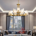Clérachic Meridian Alabaster Chandelier, fifteen lights lit above a cream sofa in a panelled room with a tall curtained window.