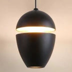 Clérachic matte black acorn pendant on a pale studio backdrop, warm light through the mid-body slit.
