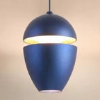 Clérachic navy acorn pendant on a beige backdrop, light spilling from the split and the base.