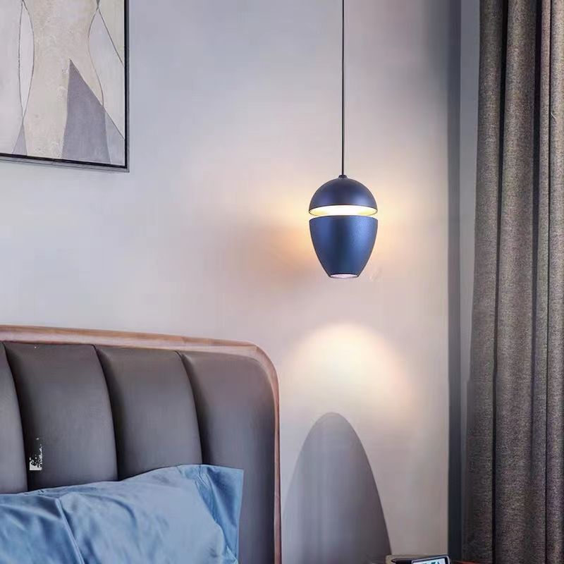 Clérachic navy acorn pendant beside a grey headboard, casting a warm pool of light on the wall.