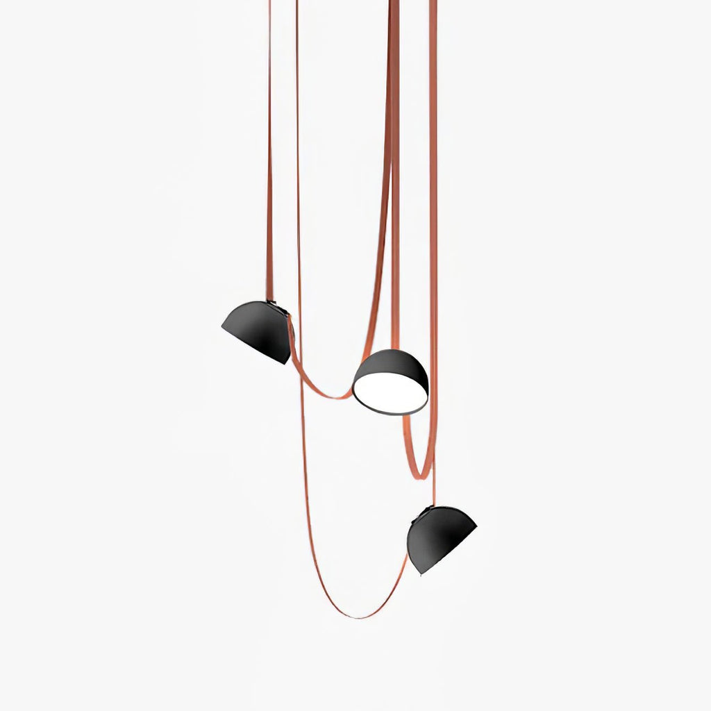 Three of these Clérachic pendant lights hang at different heights, black metal domes trailing red fabric straps on a white backdrop.