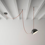A black dome on this Clérachic pendant light hangs from a red fabric strap looped from a ceiling plate across a white beamed ceiling.