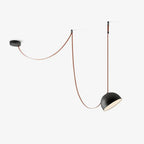 This Clérachic pendant light on a white backdrop has a black metal dome, with its red strap swooping from a round ceiling plate to a wall hook.