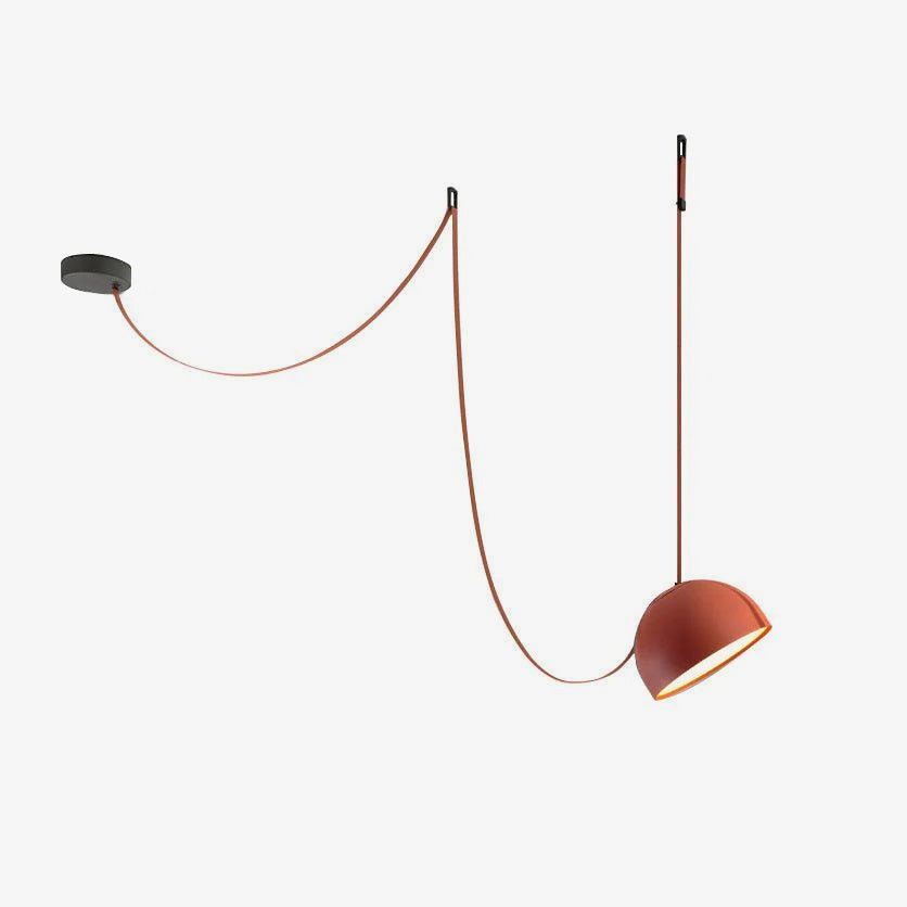 Orange-red dome version of this Clérachic pendant light, with its red fabric strap draped from a dark ceiling plate on a white backdrop.