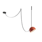 This Clérachic pendant light on a white backdrop, with an orange dome hanging from a black strap looped over a ceiling plate.