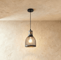 Clérachic domed black mesh pendant, 15 cm wide, with a grey stone-look collar and brass band, glowing with a bulb