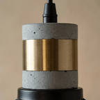 Close view of the Clérachic pendant collar, a grey speckled stone-look section with a brushed brass band