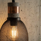 Close crop of a Clérachic mesh pendant showing the grey speckled collar, copper-toned band and filament bulb