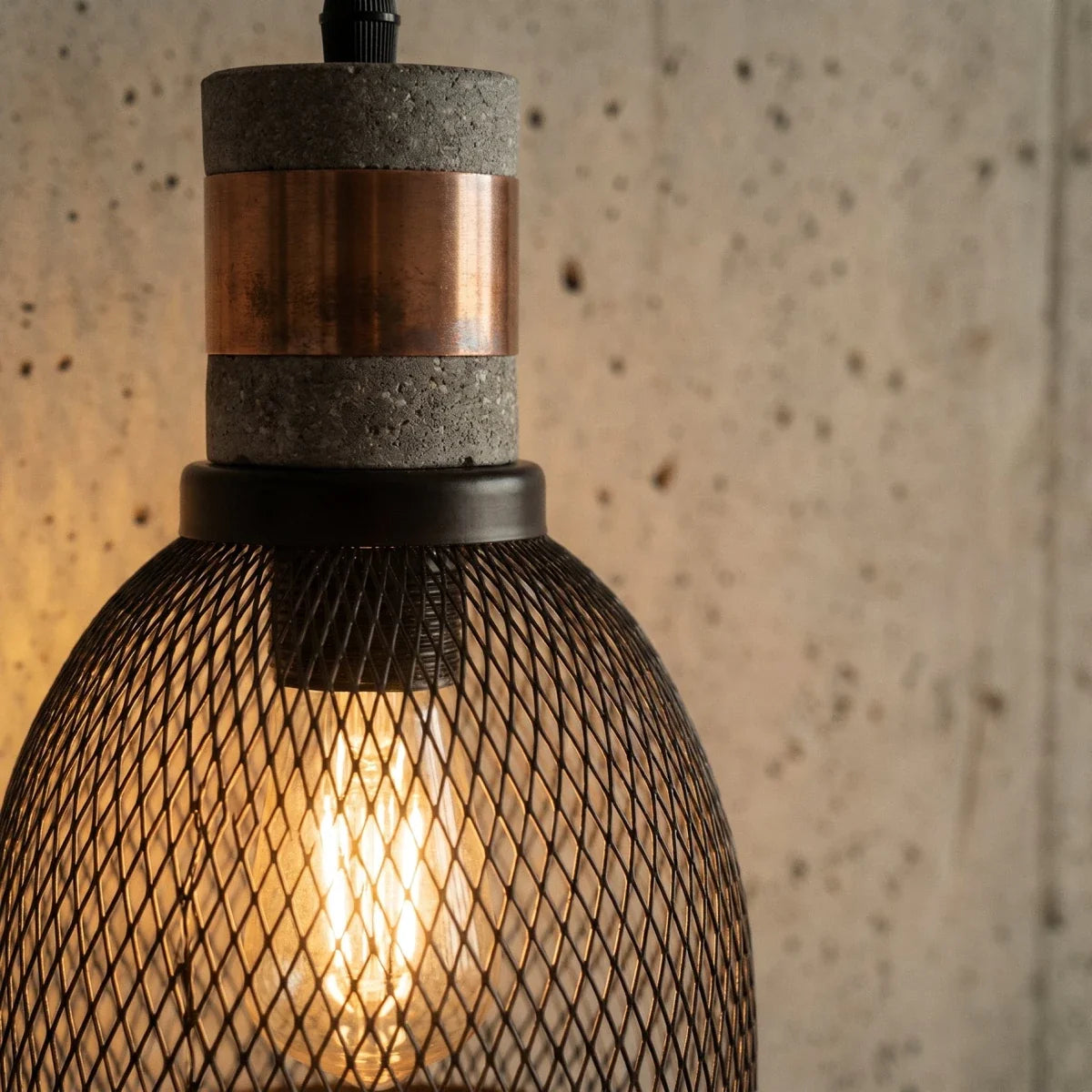Close crop of a Clérachic mesh pendant showing the grey speckled collar, copper-toned band and filament bulb