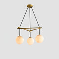 Clérachic Miira chandelier with three alabaster orbs on a slim brass frame.