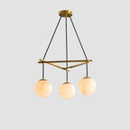 Clérachic Miira chandelier with three alabaster orbs on a slim brass frame.