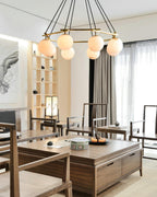 The Clérachic Miira chandelier lit above a walnut table in a bright, calm dining room.