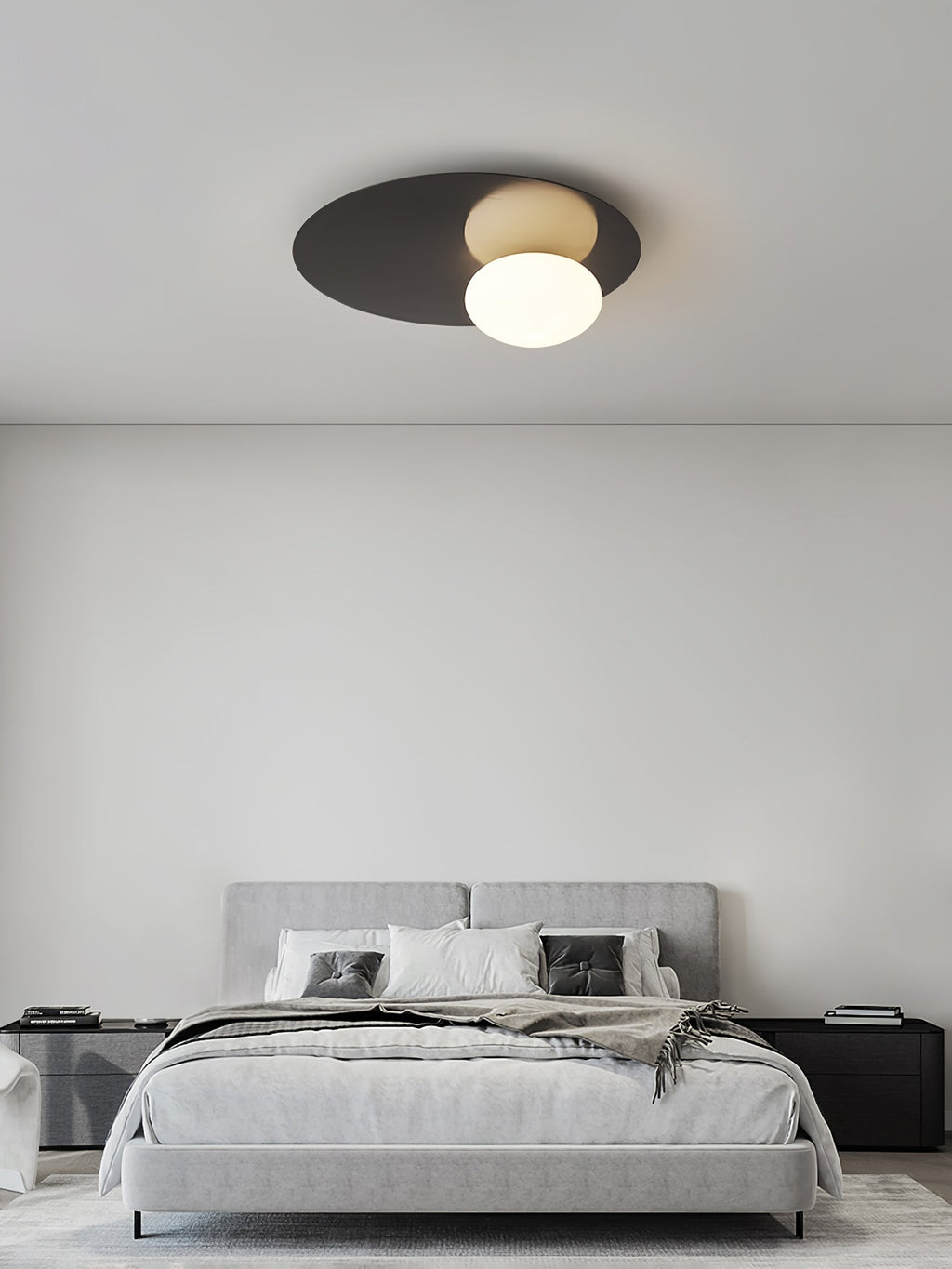 Black Clérachic ceiling light above a grey bed in a spare bedroom with a plain white wall.