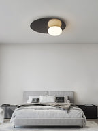 Black Clérachic ceiling light above a grey bed in a spare bedroom with a plain white wall.