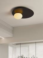 Black Clérachic ceiling light with a warm-lit globe in a beige room with a deep ceiling coffer and a slatted blind.