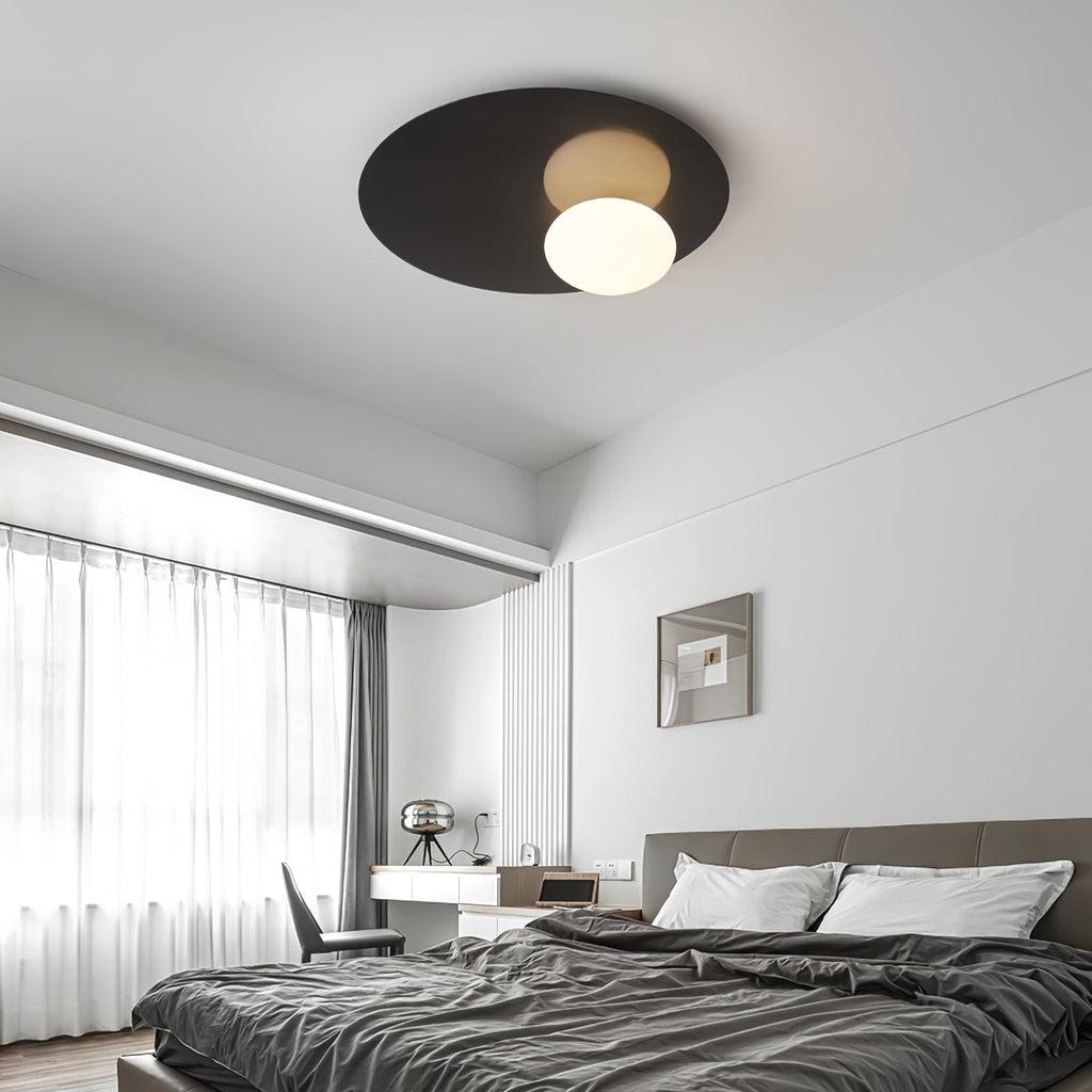 Black Clérachic ceiling light above a bedroom with dark grey bedding, a desk and tall windows with sheer curtains.