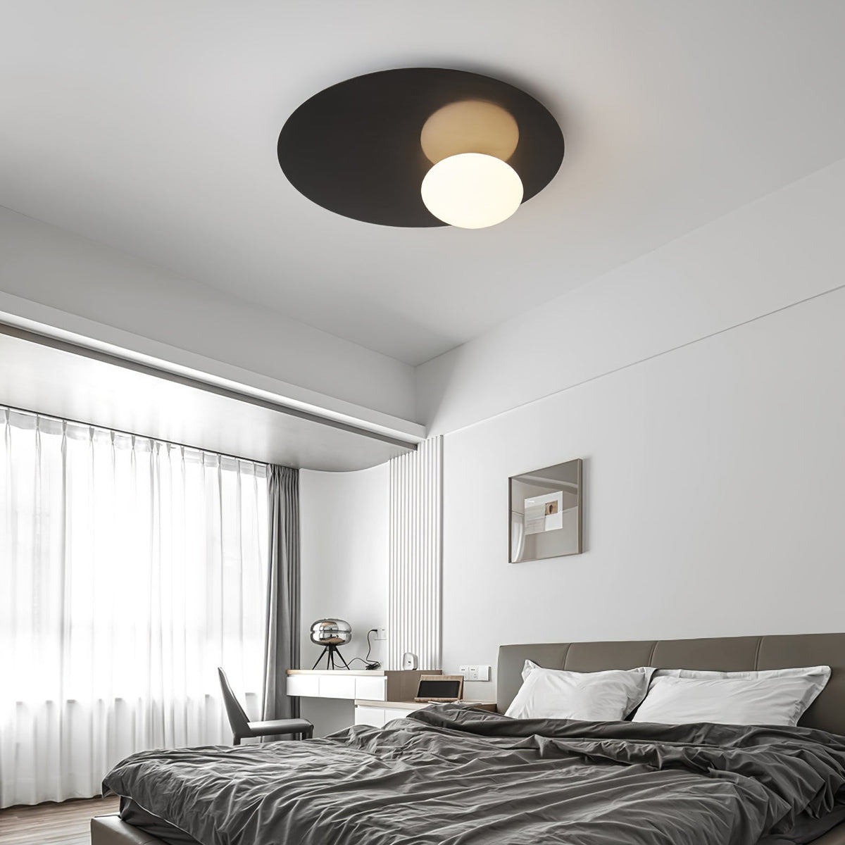 Black Clérachic ceiling light above a bedroom with dark grey bedding, a desk and tall windows with sheer curtains.