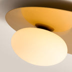 Close view of the brass disc and the opal glass globe lit warm on this Clérachic ceiling light.