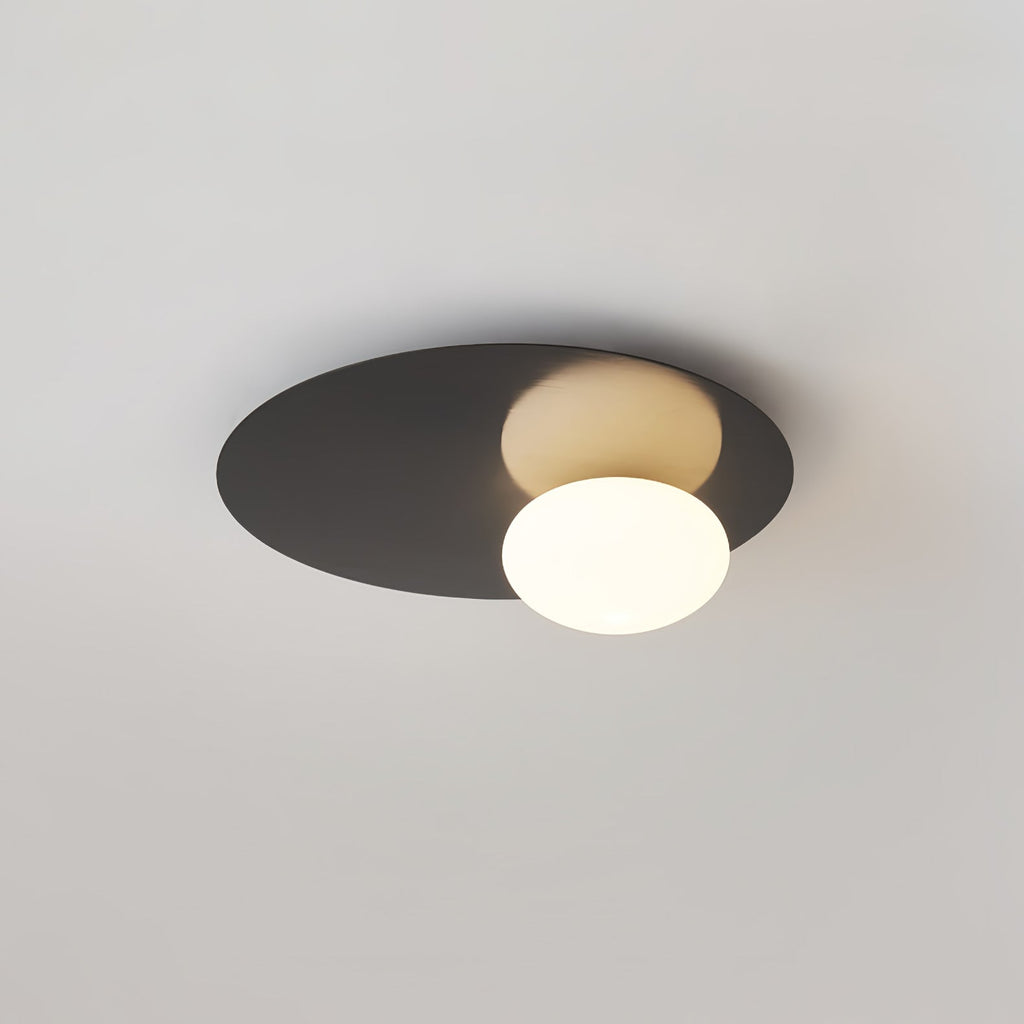 Black Clérachic ceiling light with a lit globe, with the disc shape clear against a light grey ceiling.