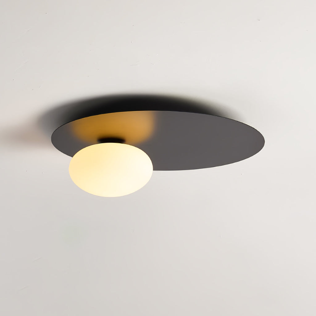 Black Clérachic ceiling light lit, with the globe's warm glow showing on the underside of the disc.