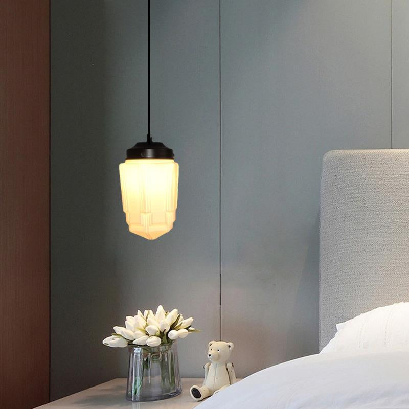 Clérachic milk glass pendant light in its stepped Art Deco shade, hung low beside a bed over a nightstand of white tulips.