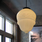 Close-up of the Clérachic milk glass pendant light showing the tiered shade's embossed floral relief and matte black cap.
