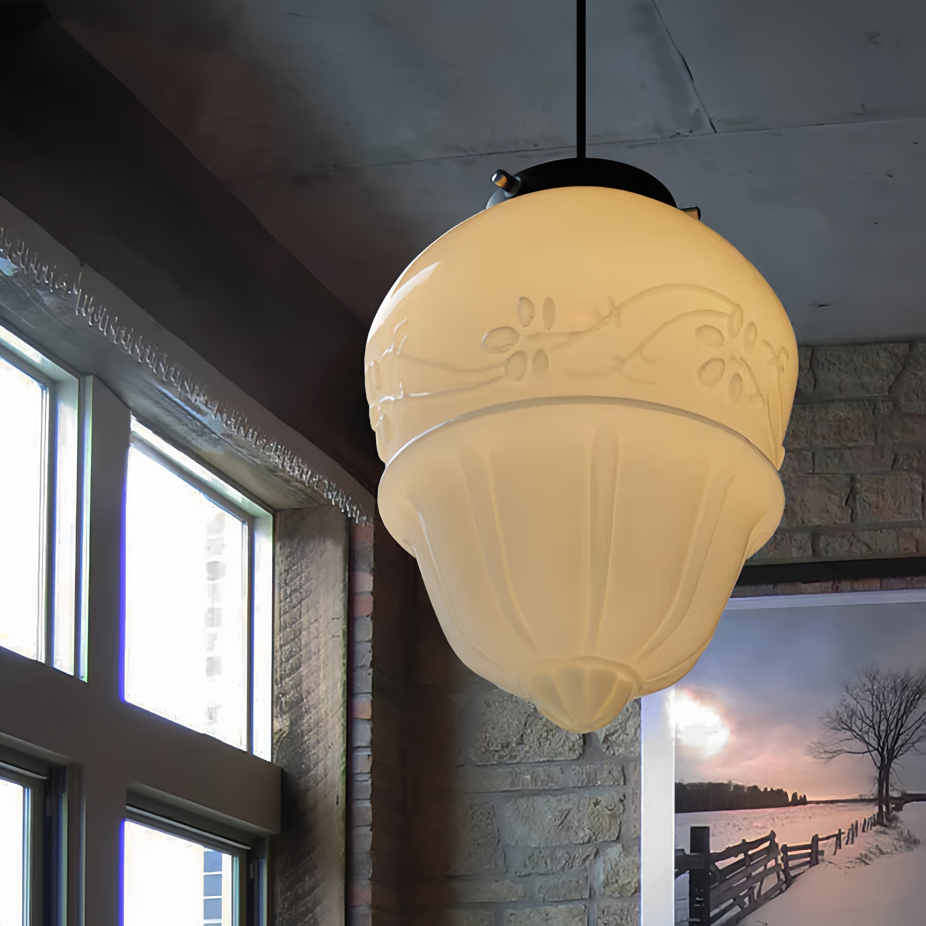 Close-up of the Clérachic milk glass pendant light showing the tiered shade's embossed floral relief and matte black cap.