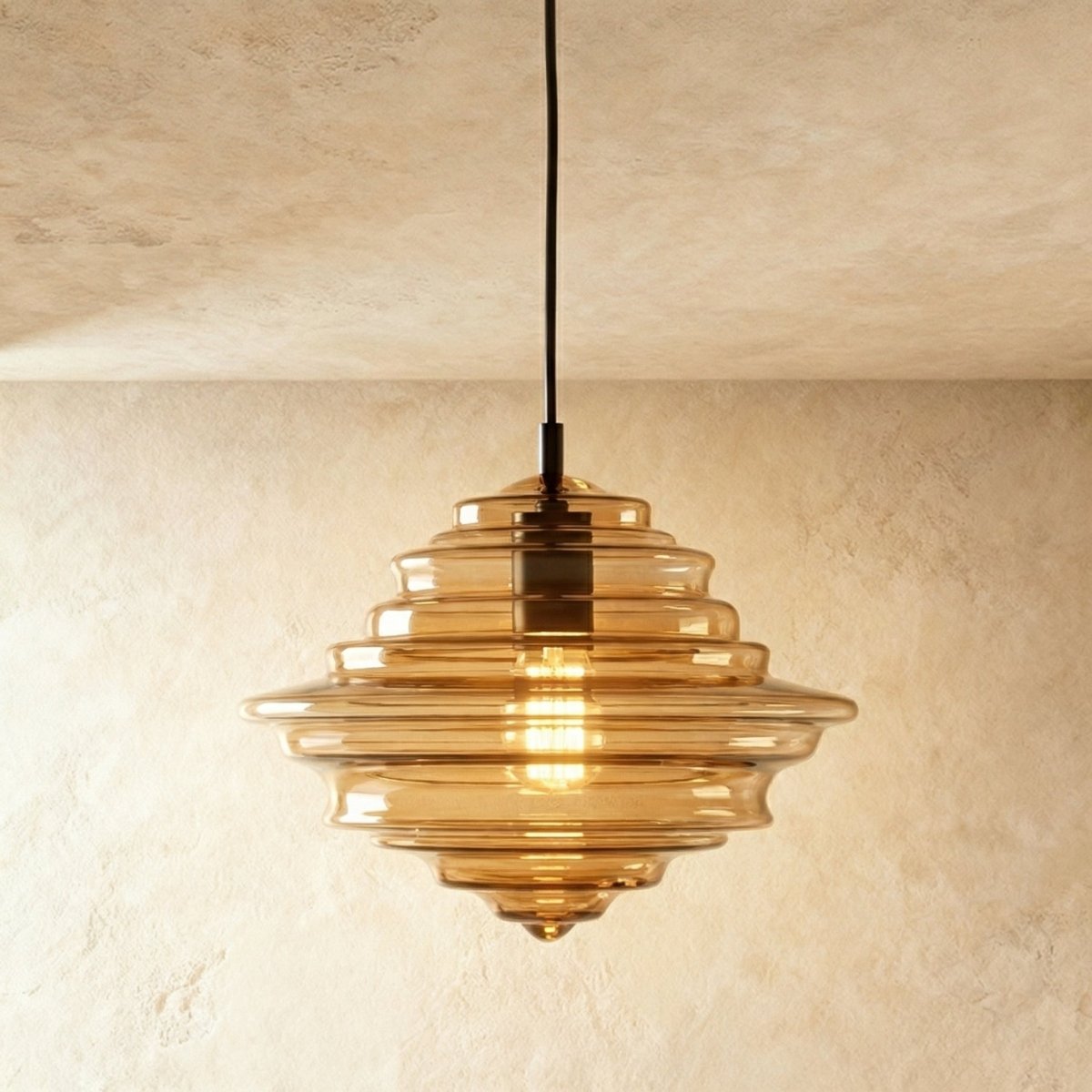 A closer view of the Clérachic pendant light in cognac glass, its tiered ribbed shade glowing warm overhead.