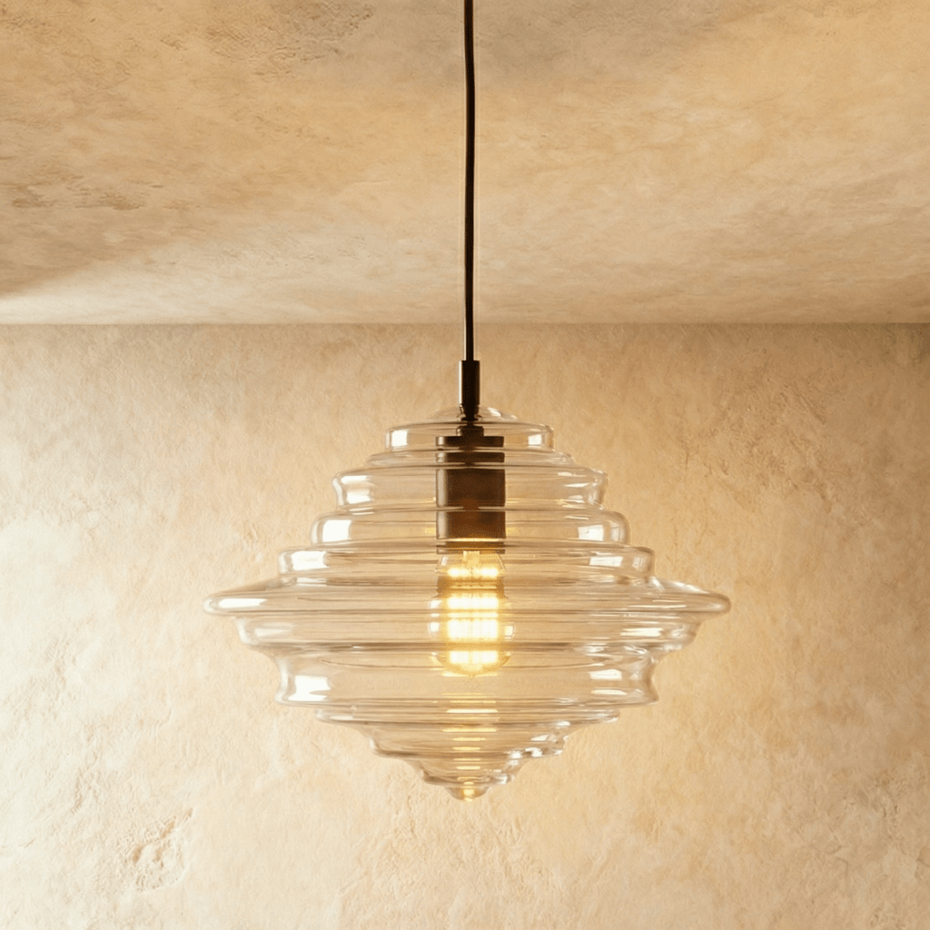 A closer view of the Clérachic pendant light in clear glass, its tiered ribbed shade glowing warm overhead.