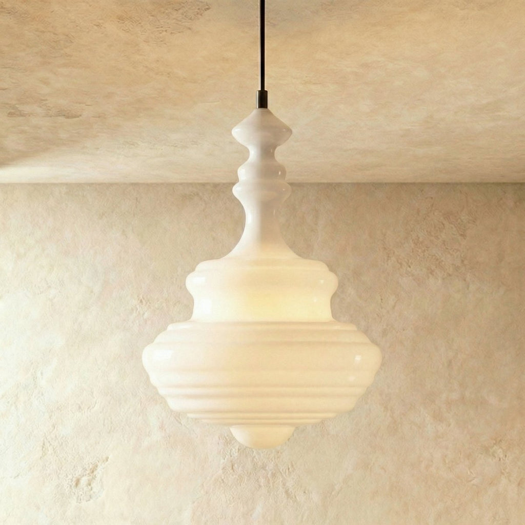 Clérachic's pendant light in milk white glass, a tall fluted decanter-shaped shade glowing softly overhead.