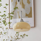 Clérachic pendant light lit, the glow through the shade in a quiet room.