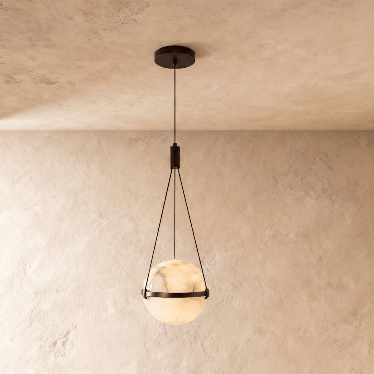 Clérachic alabaster globe pendant lit from within, held by three fine cords in a dark bronze band, on a limewash wall.