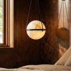 Clérachic close view of a lit alabaster globe pendant with a dark band, casting a shadow on burr walnut panelling.