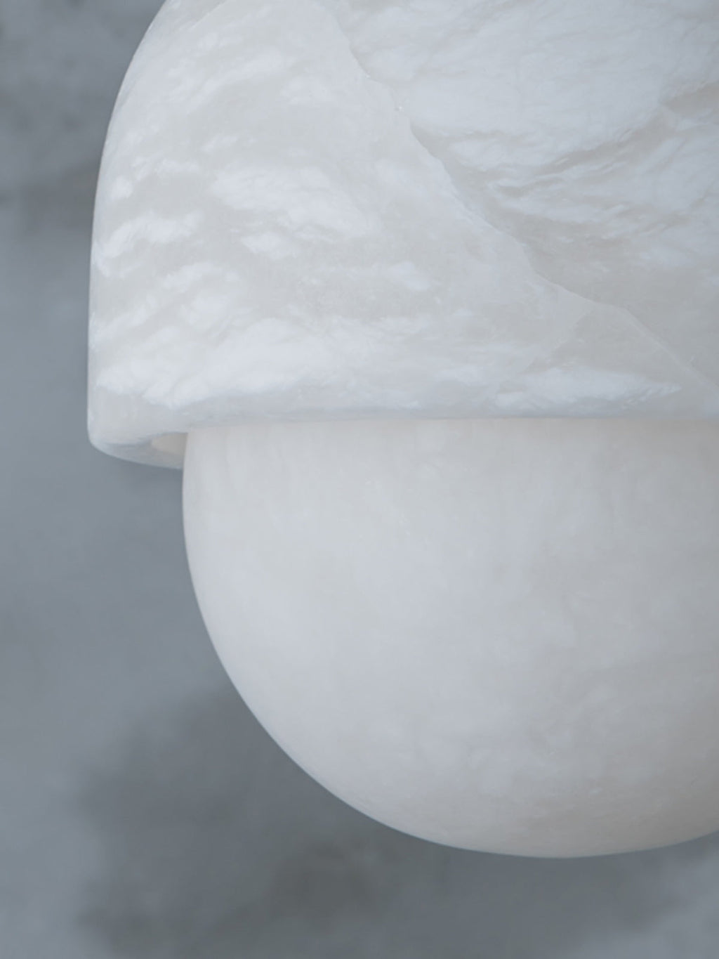 Macro of the alabaster cap and sphere on the Clérachic Mini Alabaster Globe Pendant, the stone's cloudy grain in view.