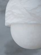 Macro of the alabaster cap and sphere on the Clérachic Mini Alabaster Globe Pendant, the stone's cloudy grain in view.