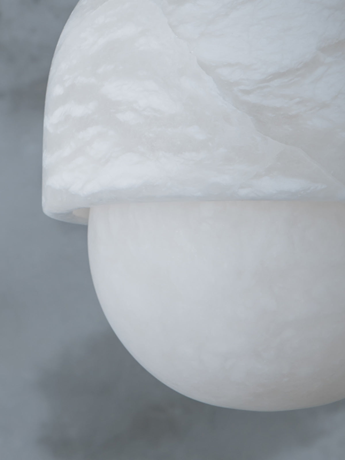 Macro of the alabaster cap and sphere on the Clérachic Mini Alabaster Globe Pendant, the stone's cloudy grain in view.