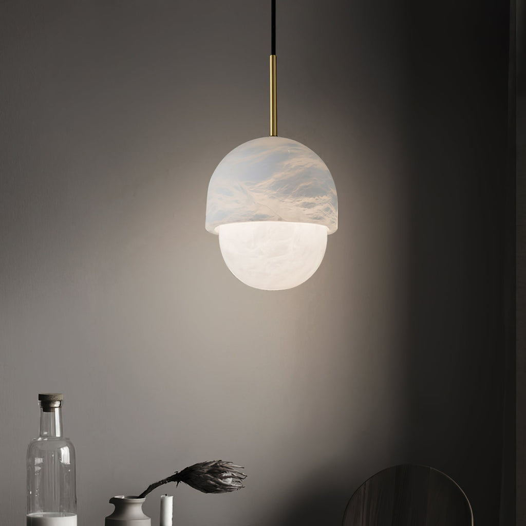 Clérachic Mini Alabaster Globe Pendant lit over a dark sideboard set with a glass bottle and a dried flower.