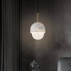 Clérachic Mini Alabaster Globe Pendant glowing against a near-black textured wall beside a floor-length curtain.