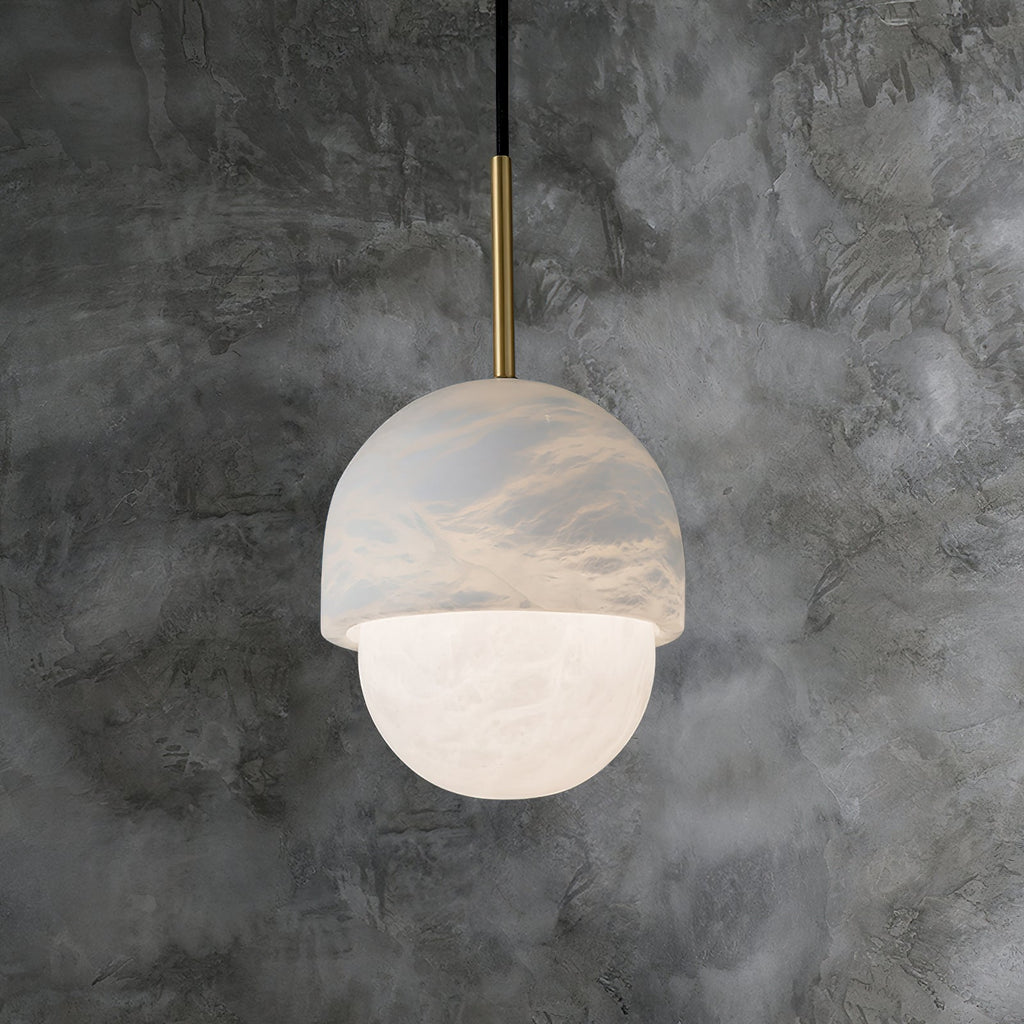 Clérachic Mini Alabaster Globe Pendant hung against mottled grey concrete, warm light spilling from the lower globe.