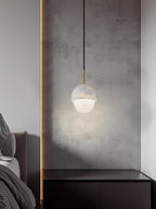 Clérachic Mini Alabaster Globe Pendant lighting a dark nightstand, its glow washing the concrete panel behind.